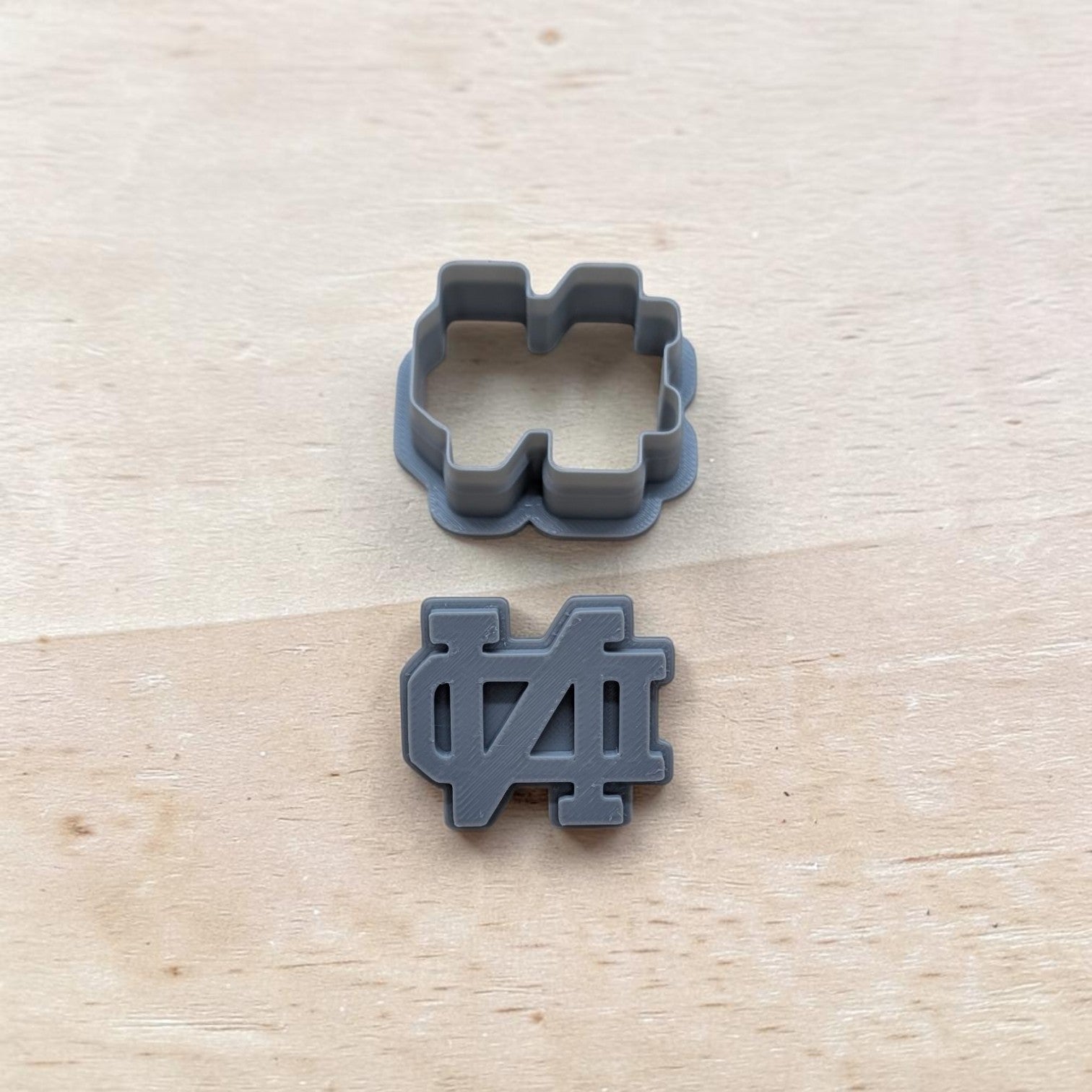 Two‑piece ND‑inspired cutter and stamp set, 3D‑printed gray plastic, displayed on wooden background for baking and crafting.
