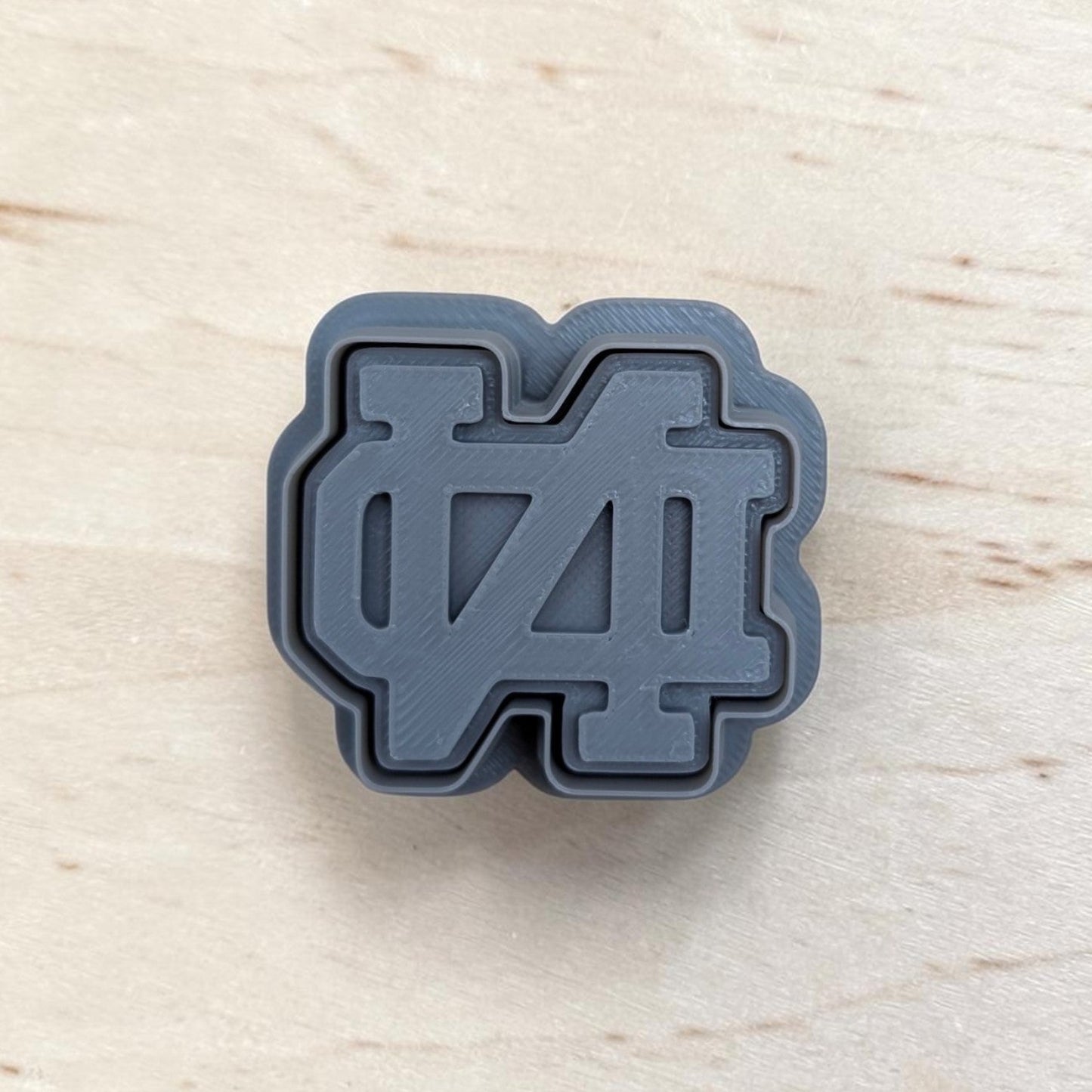 Gray ND‑style cookie cutter and matching stamp set on light wood surface, ideal for cookies, fondant, and polymer clay crafts.