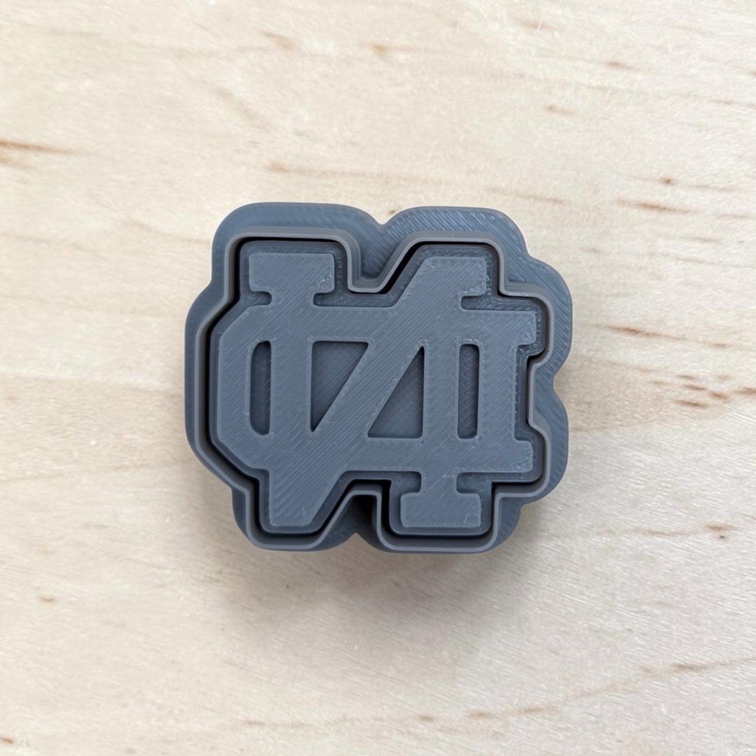 Gray ND‑style cookie cutter and matching stamp set on light wood surface, ideal for cookies, fondant, and polymer clay crafts.