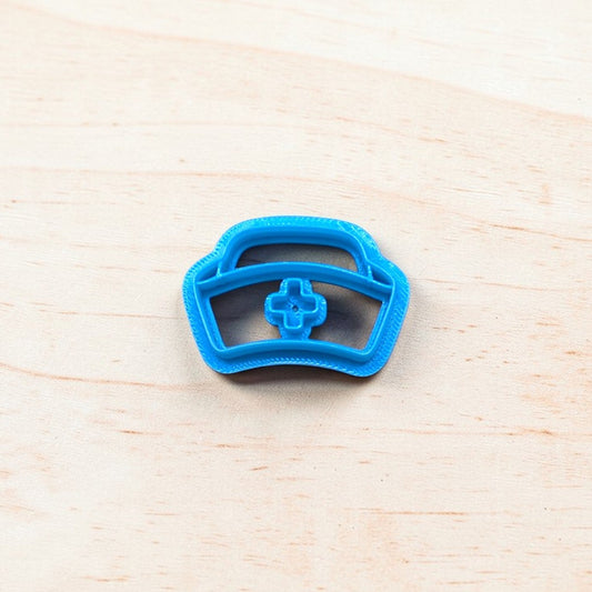 Blue cookie cutter shaped like a nurse cap on a light wooden surface