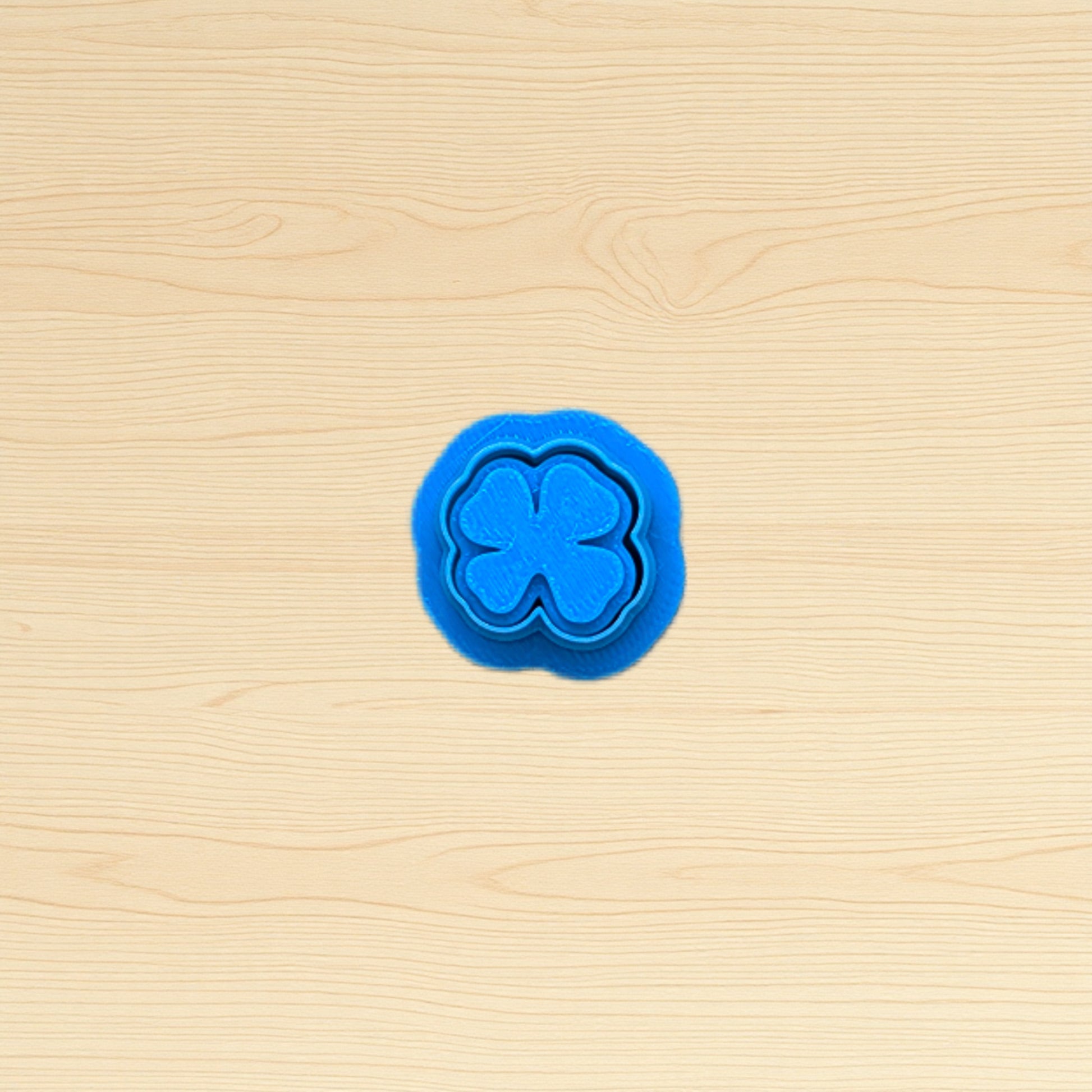Blue four-leaf clover cookie cutter on a wooden surface