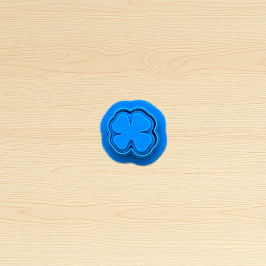 Blue four-leaf clover cookie cutter on a wooden surface
