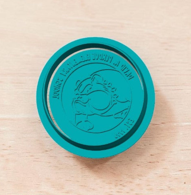Teal DAPES Bulldog Mascot cookie stamp showing reversed text on wooden surface — custom embossing stamp for cookies, fondant, and clay.