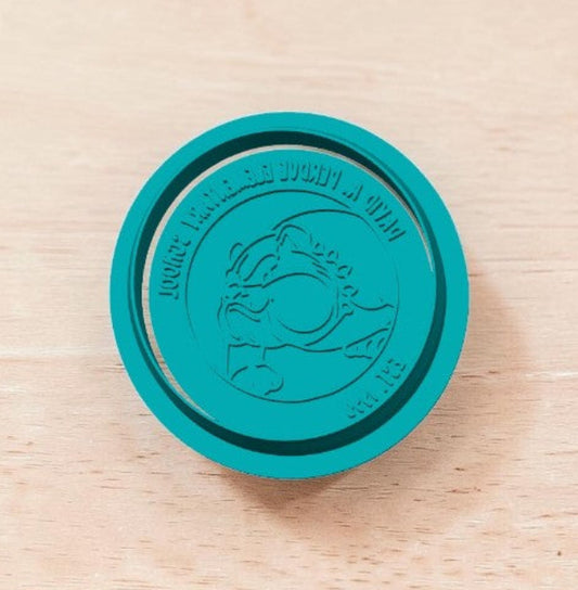 Teal DAPES Bulldog Mascot cookie stamp showing reversed text on wooden surface — custom embossing stamp for cookies, fondant, and clay.