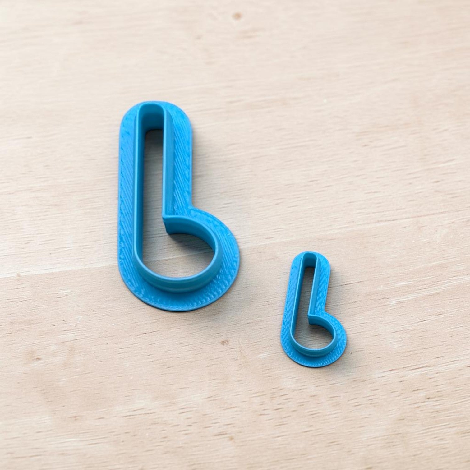 Set of two blue 3D printed polymer clay cutters in small and large sizes on wood background