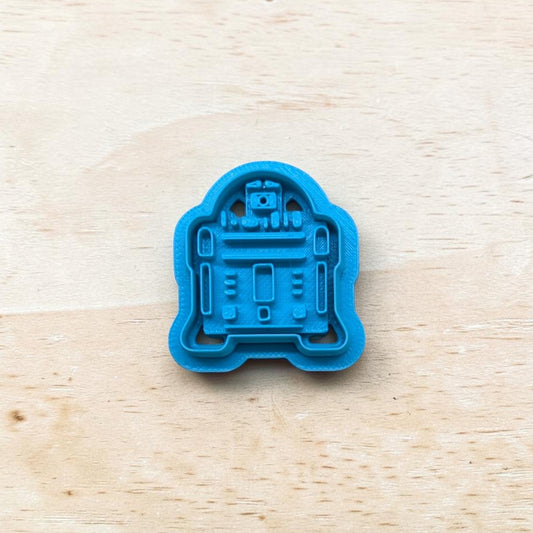 plastic R2-D2 cookie cutter on a light color wood surface