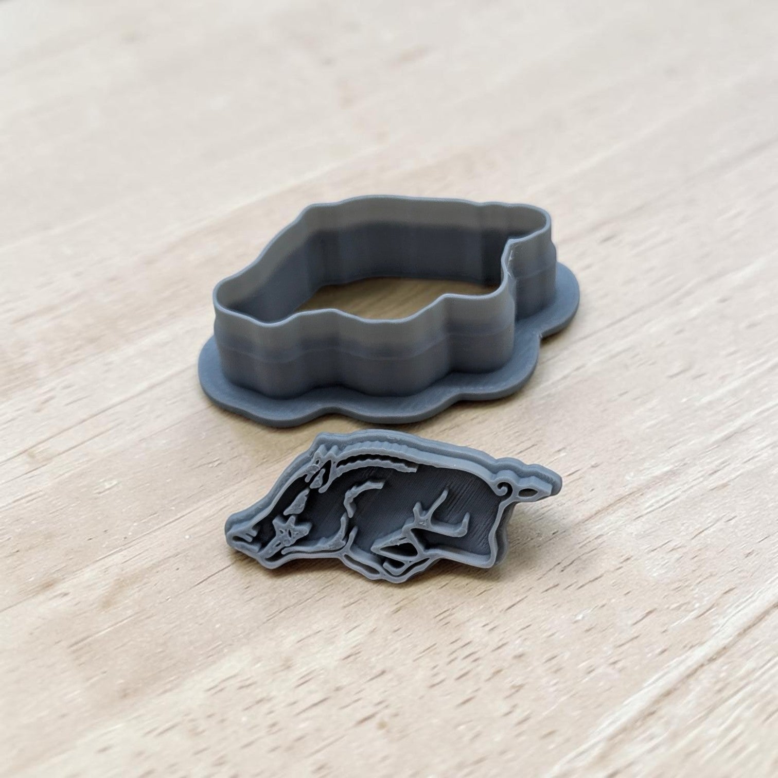 3D printed gray razorback cookie cutter and detailed stamp set on light wood surface, perfect for cookies, fondant, polymer clay, and pottery crafting