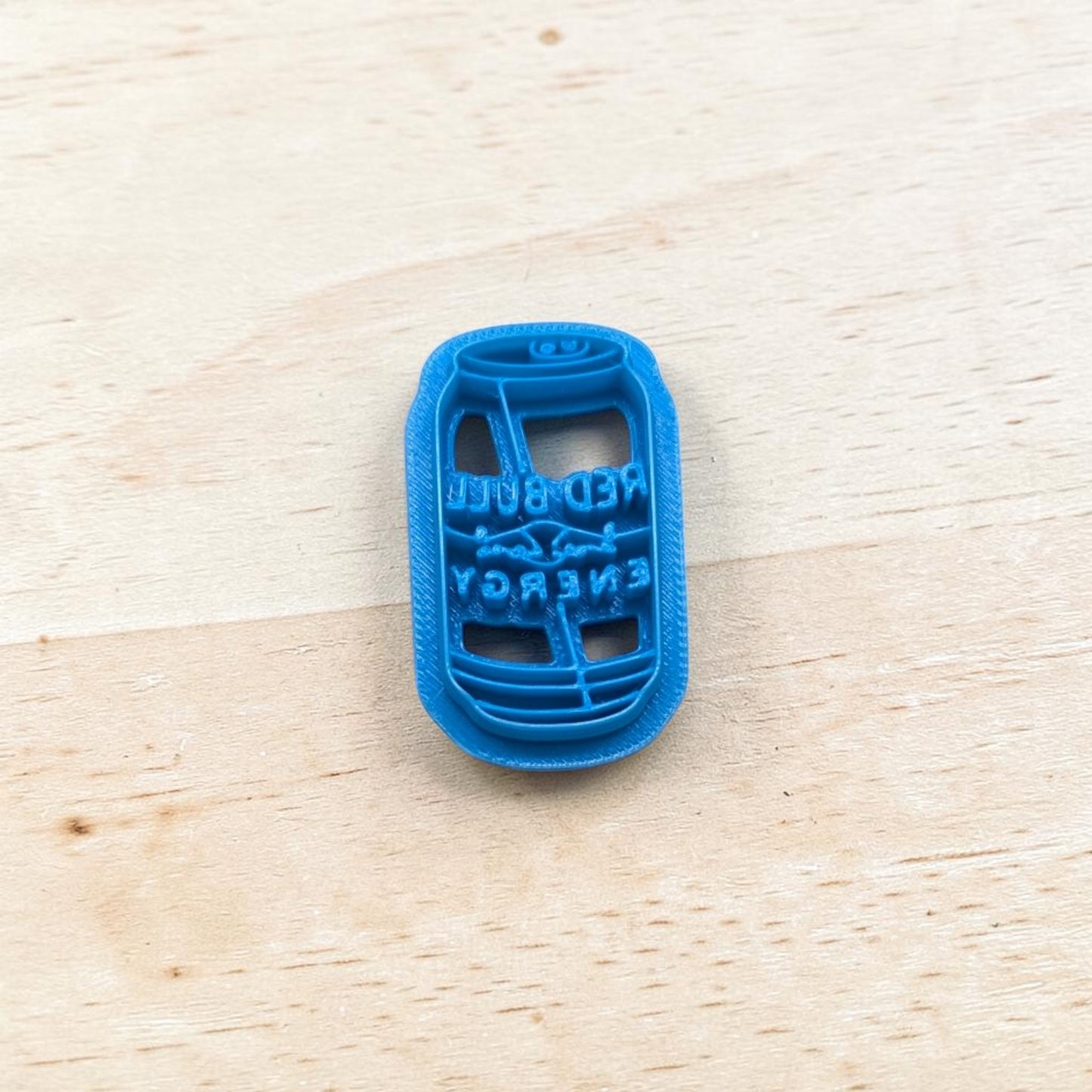 Blue plastic Red Bull energy drink can cookie cutter on a wooden surface