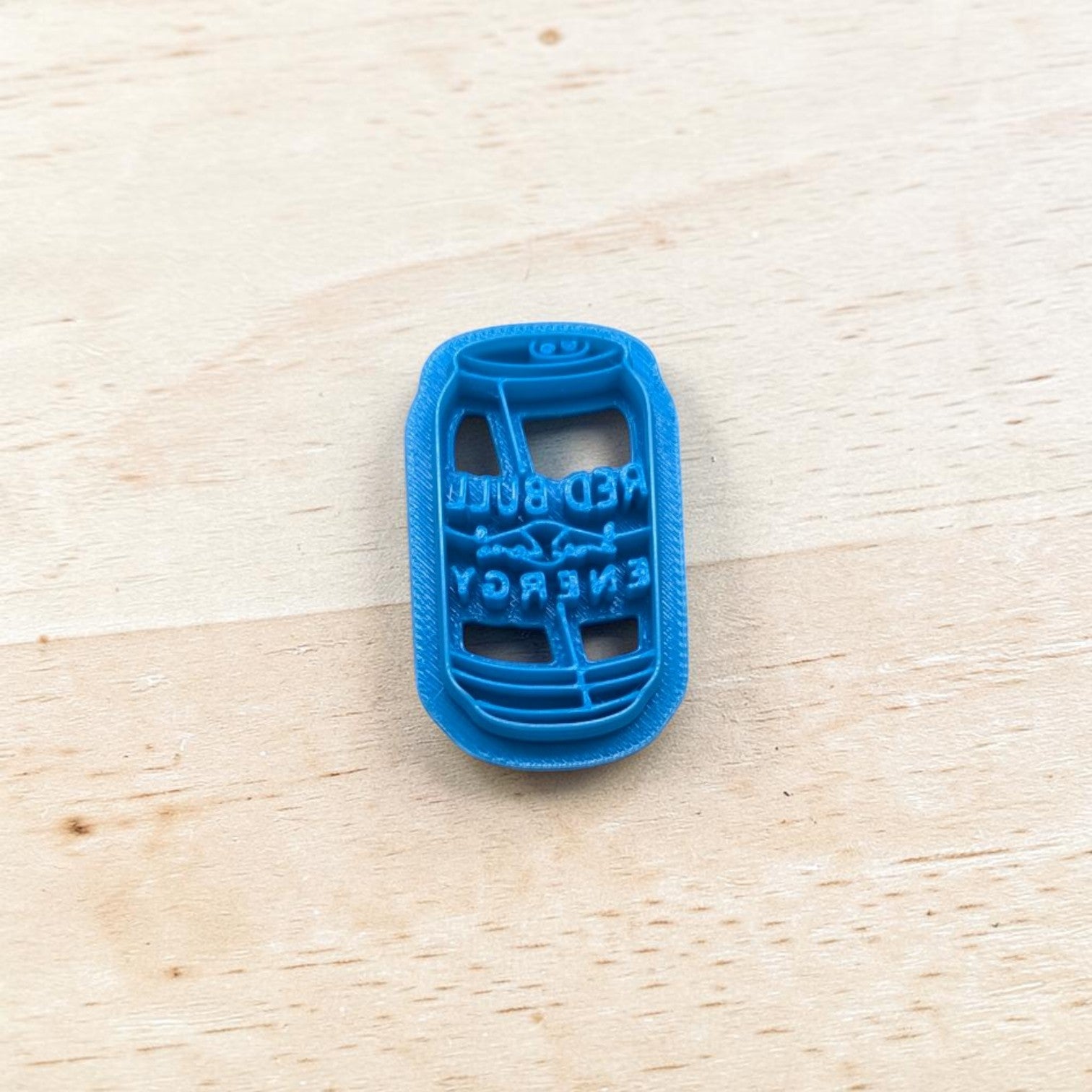 Blue plastic Red Bull energy drink can cookie cutter on a wooden surface