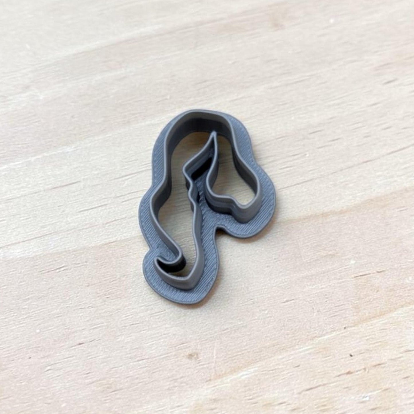 Single gray 3D‑printed hair‑silhouette cookie cutter resting on light wood tabletop — ideal for cookies, ceramics, pottery, or polymer clay crafting.