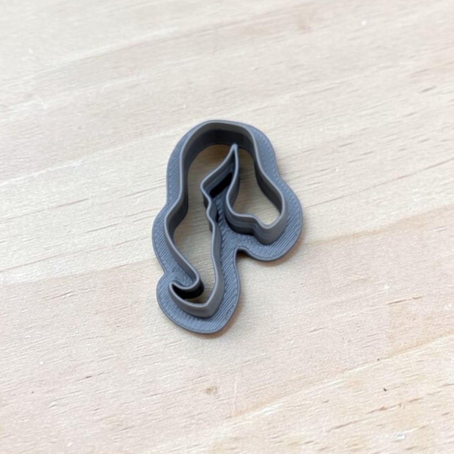 Single gray 3D‑printed hair‑silhouette cookie cutter resting on light wood tabletop — ideal for cookies, ceramics, pottery, or polymer clay crafting.