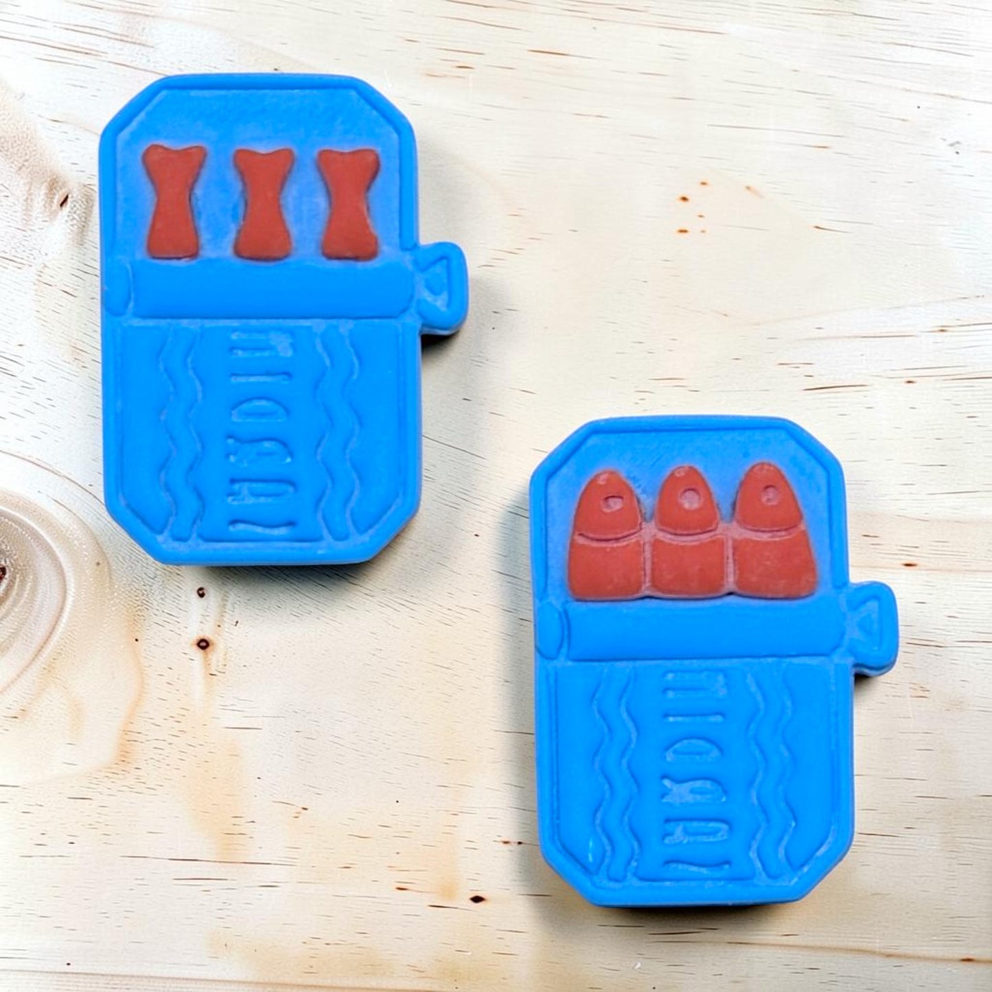 Two blue cookie cutters with red shapes on a wooden surface