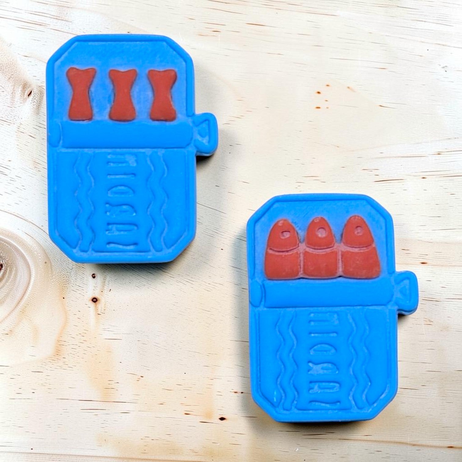 Two blue cookie cutters with red shapes on a wooden surface