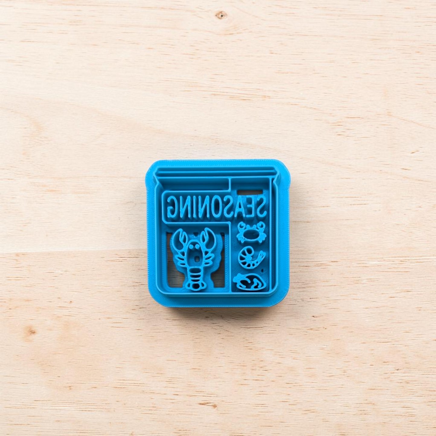 Blue seasoning container with lobster design on a wooden surface