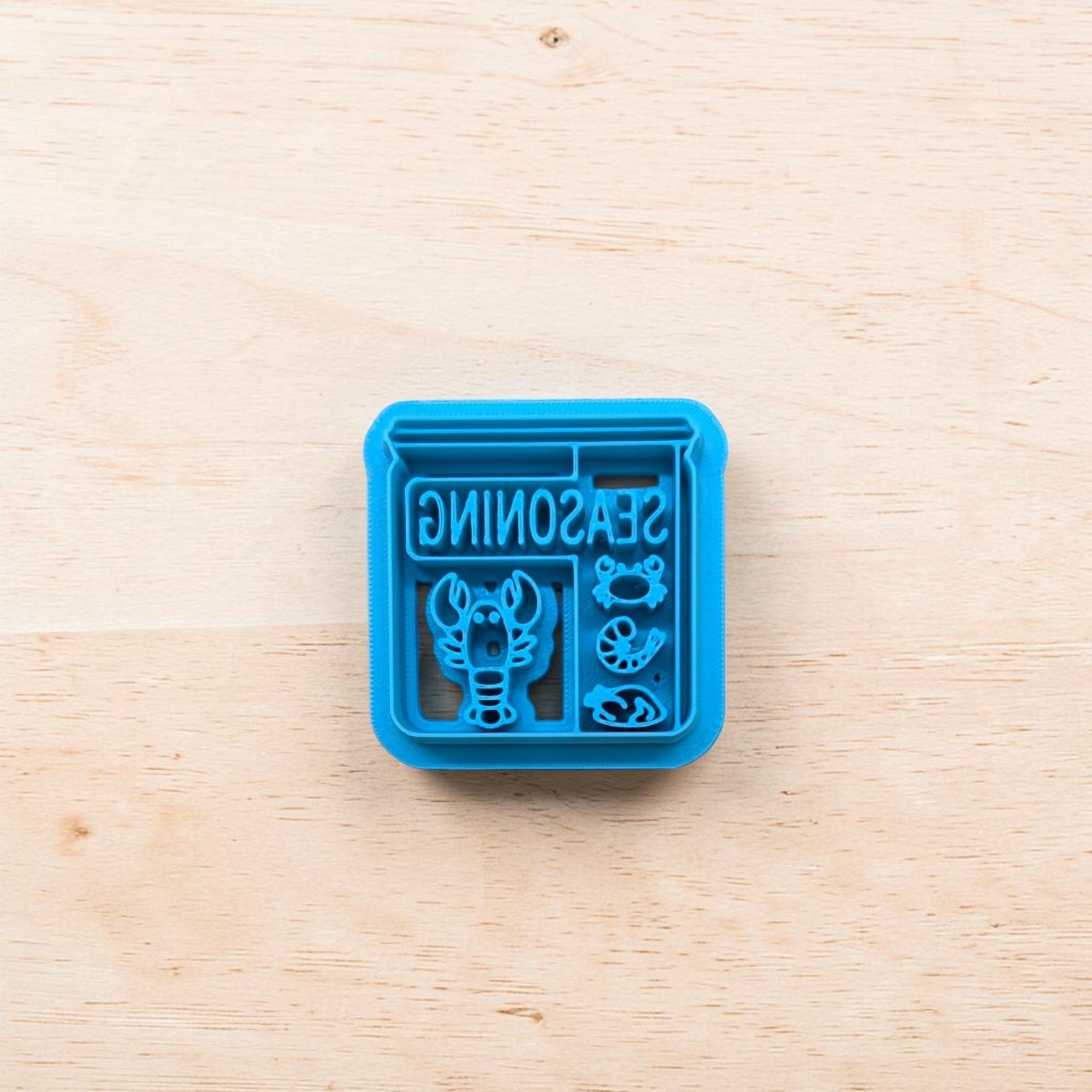 Blue seasoning container with lobster design on a wooden surface