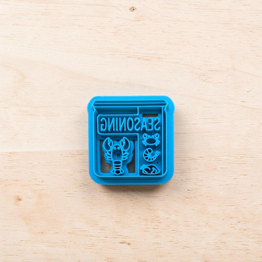 Blue seasoning container with lobster design on a wooden surface