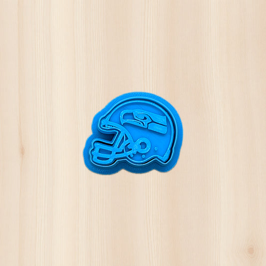 Seattle Seahawks football helmet cookie cutter with embossed detail, displayed on a wooden background, 3D printed plastic baking and clay tool for cookies, fondant, and polymer clay crafts.