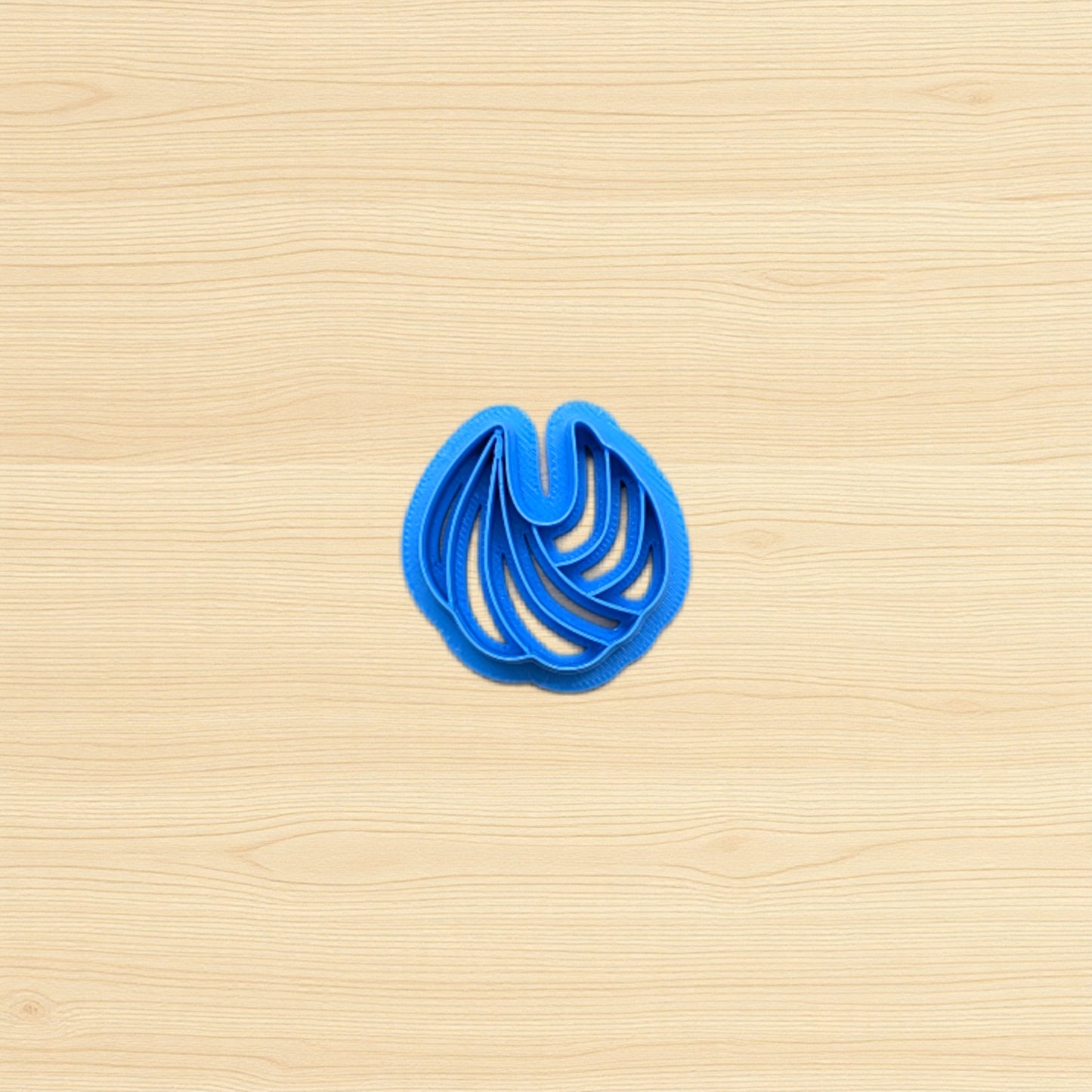 Blue cookie cutter shaped like a shell on a wooden surface