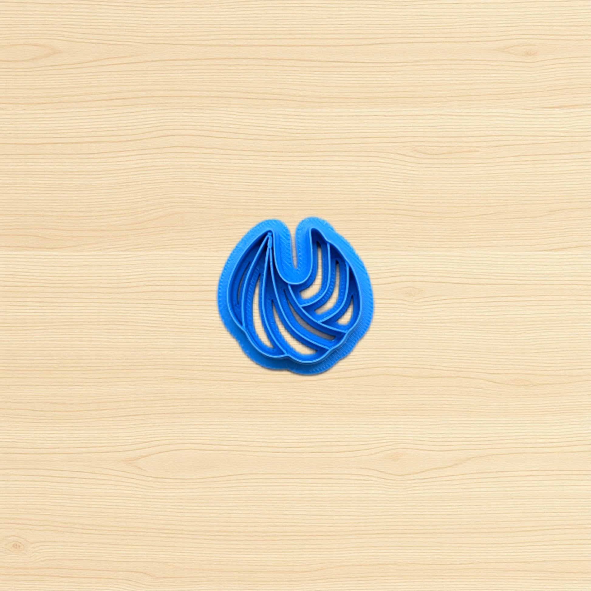 Blue cookie cutter shaped like a shell on a wooden surface