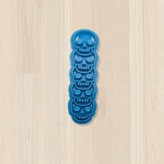 Blue skull-shaped cookie cutter on a light wood surface