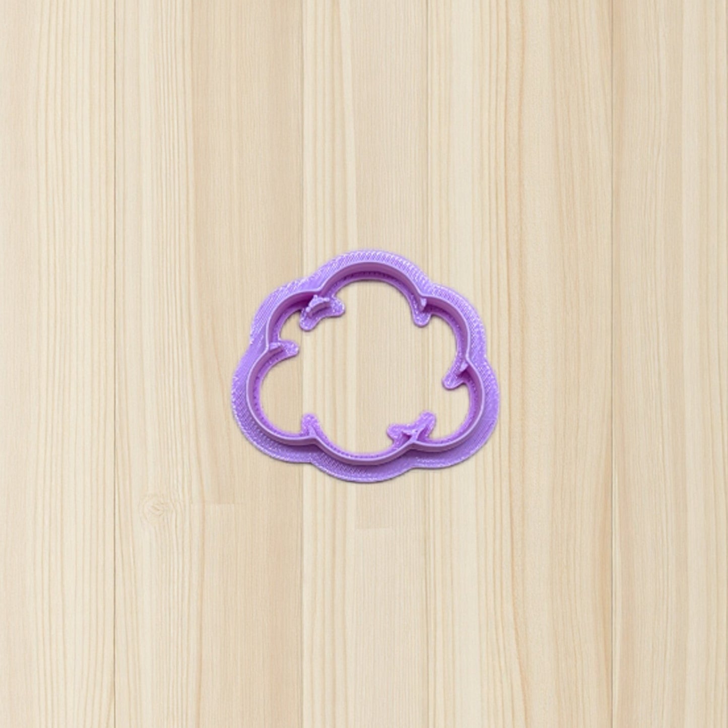 purple plastic smoke puff cloud cookie cutter on a wooden surface