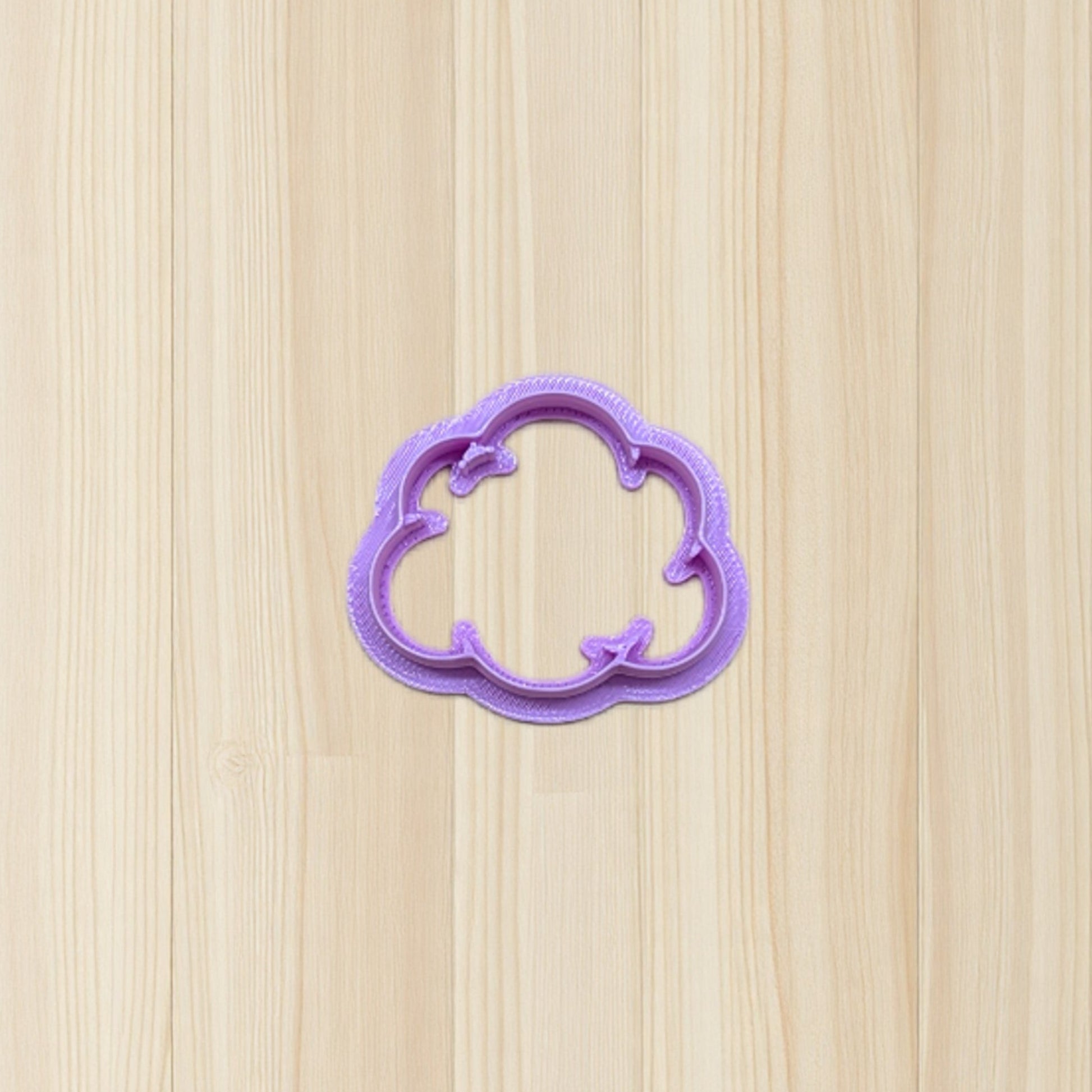 purple plastic smoke puff cloud cookie cutter on a wooden surface