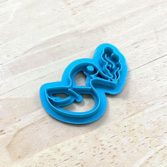 Blue cookie cutter shaped like a smoking duck on a light wooden surface