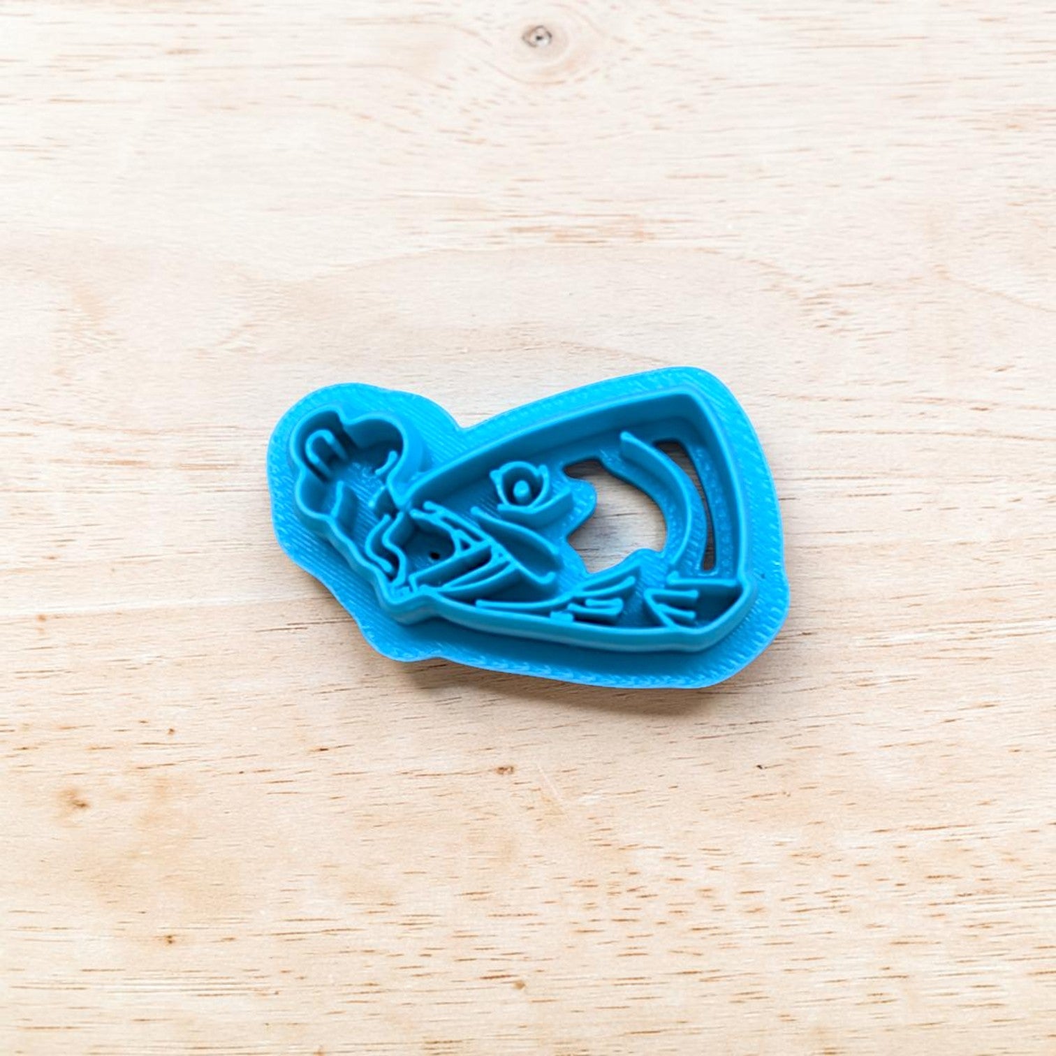 Blue cookie cutter shaped like a fish on a wooden surface