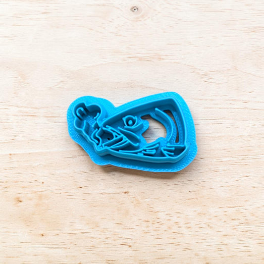 Blue cookie cutter shaped like a fish on a wooden surface