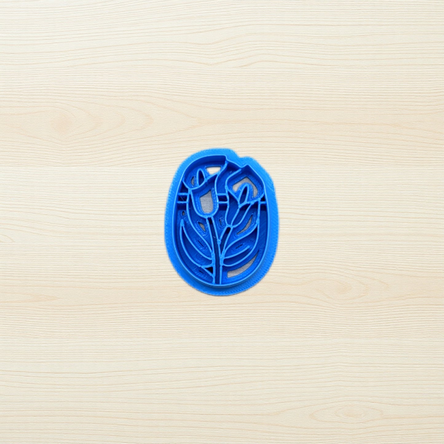 Blue cookie cutter with floral design on a beige surface