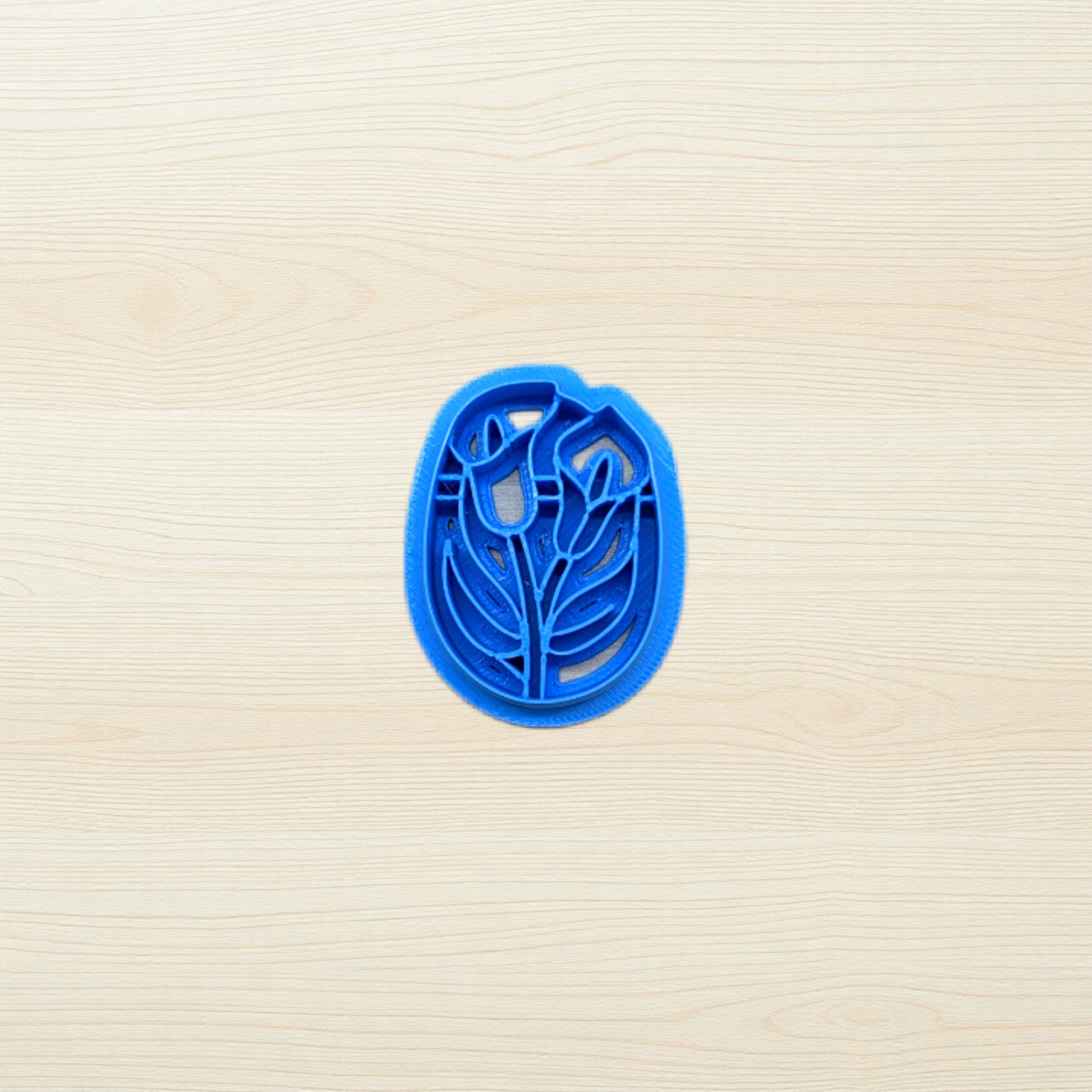 Blue cookie cutter with floral design on a beige surface