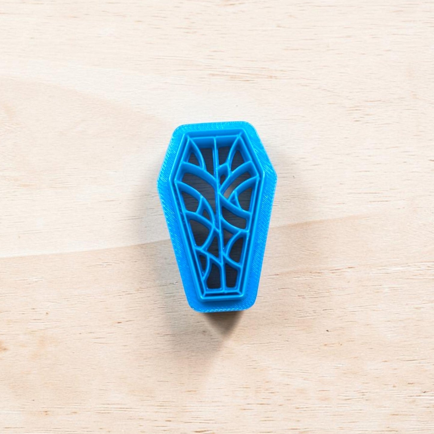 Blue coffin-shaped cookie cutter on a wooden surface