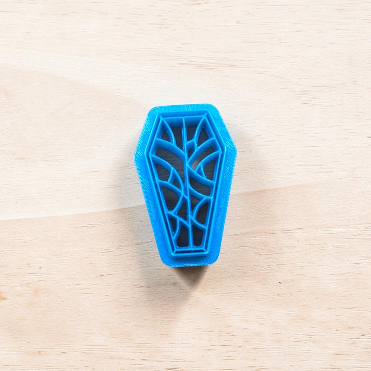 Blue coffin-shaped cookie cutter on a wooden surface