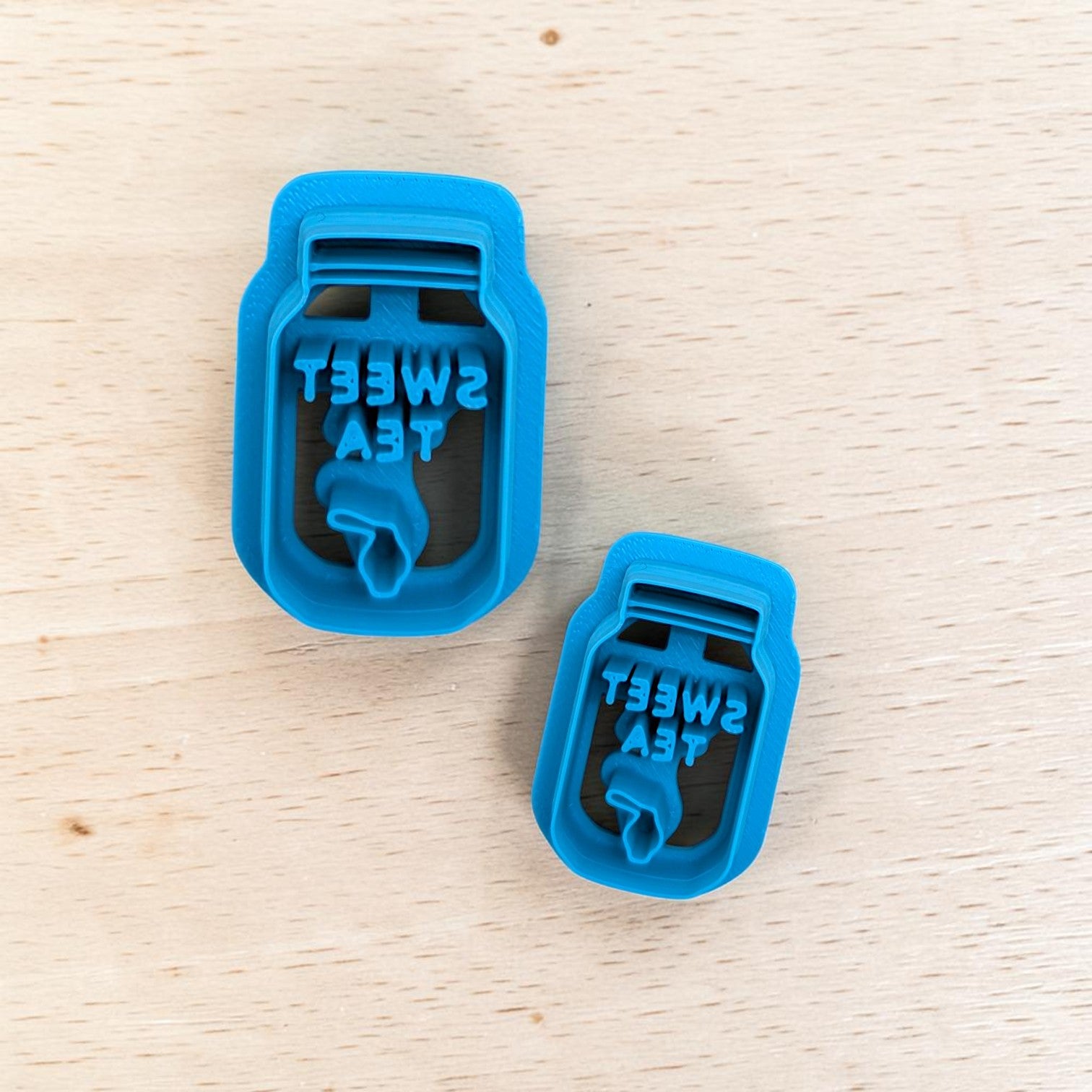 Two blue plastic tea mason jars with 'Sweet Tea' text on a wooden surface