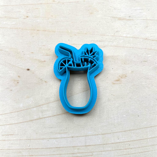 Blue cookie cutter shaped like a tropical drink on a light wooden surface