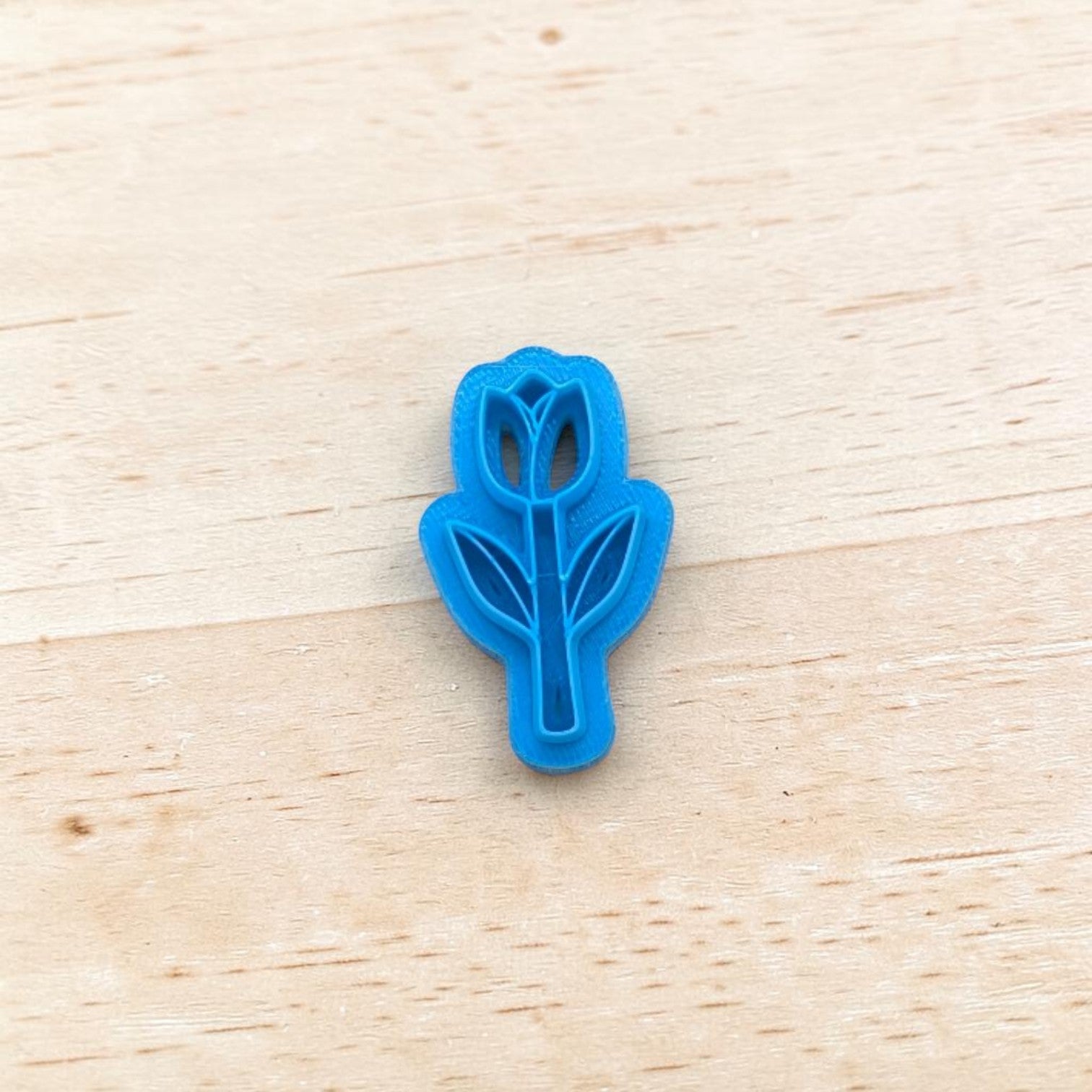Blue tulip-shaped cookie cutter on a wooden surface