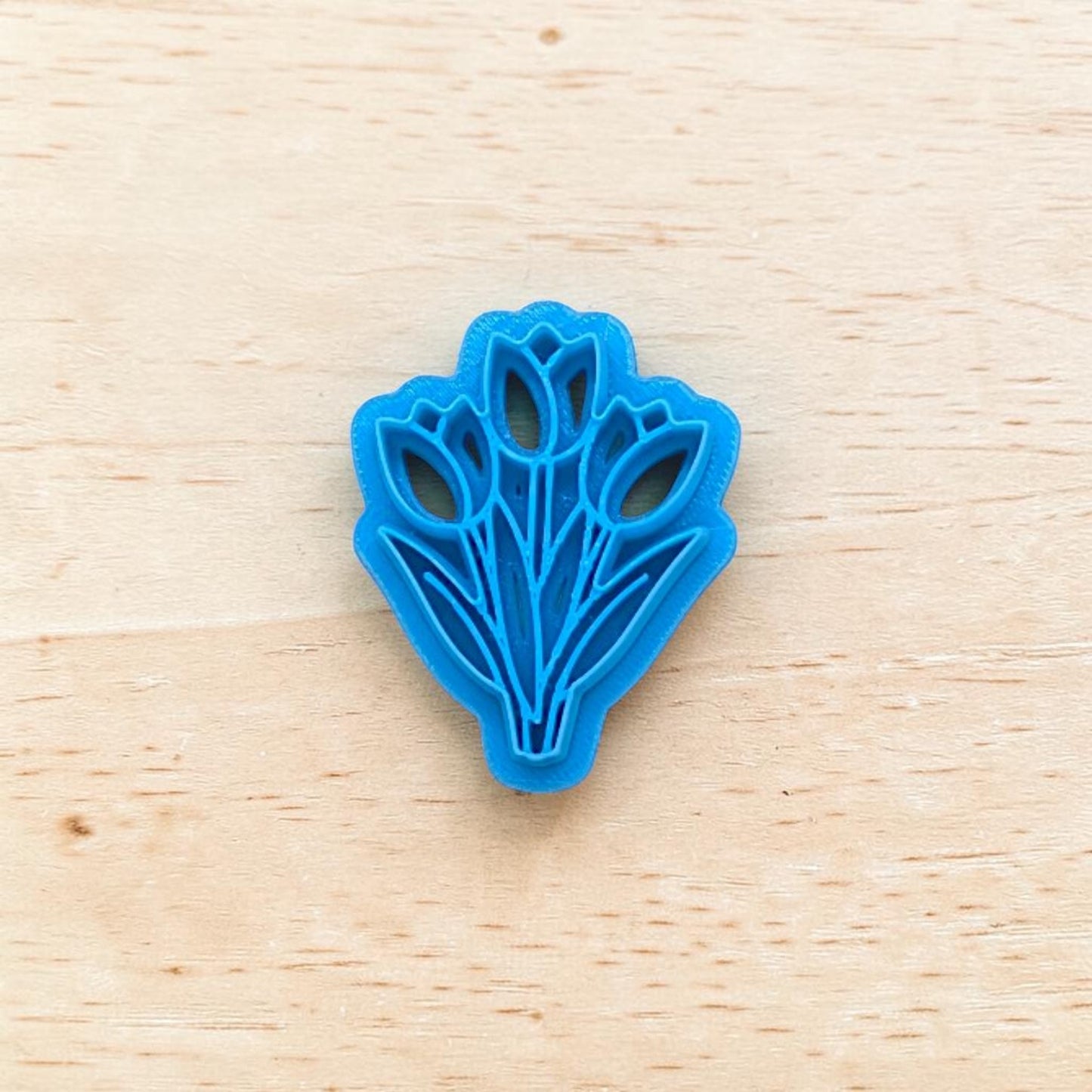 Blue tulip-shaped cookie cutter on a wooden surface