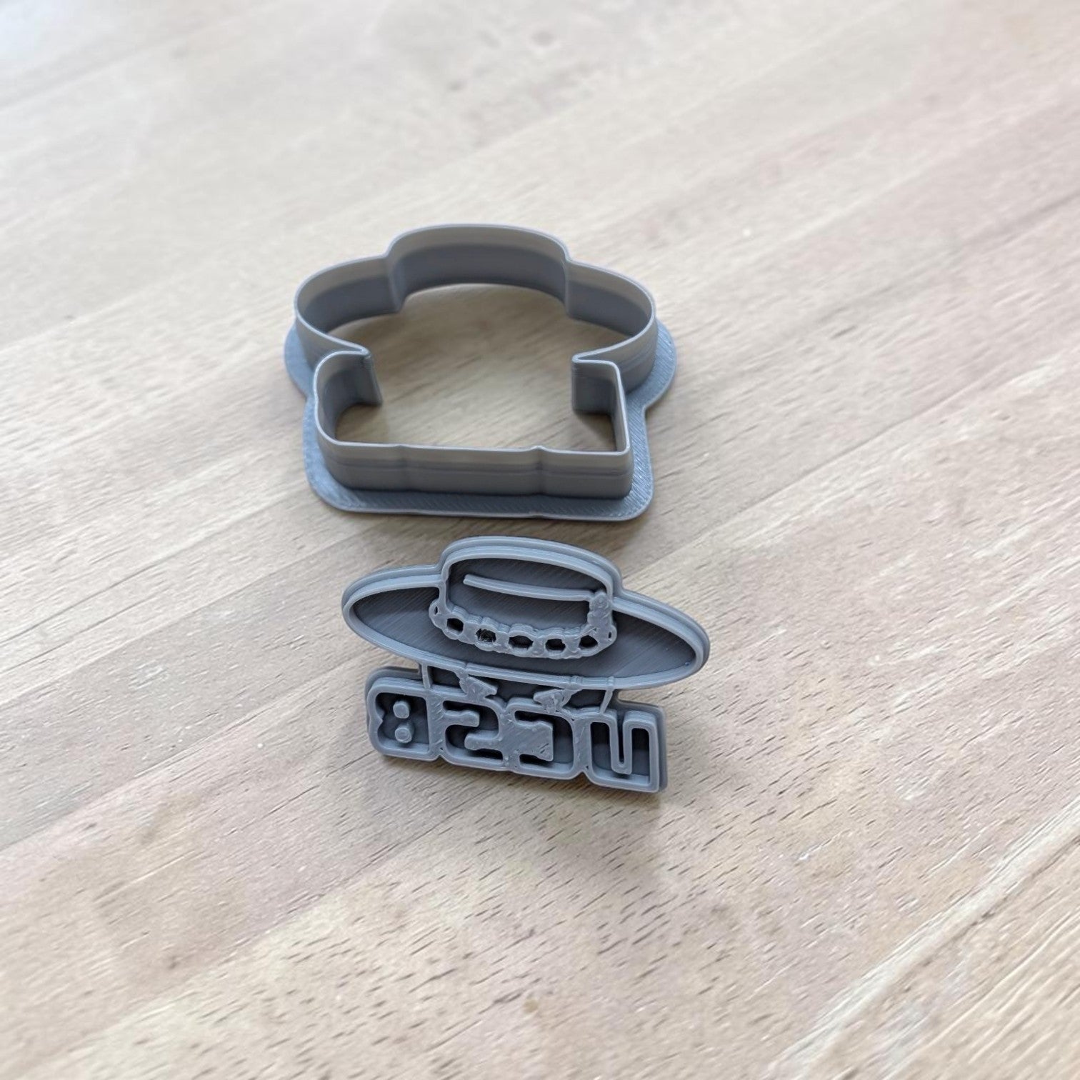 Two gray plastic cookie cutters on a light wood grain surface. 