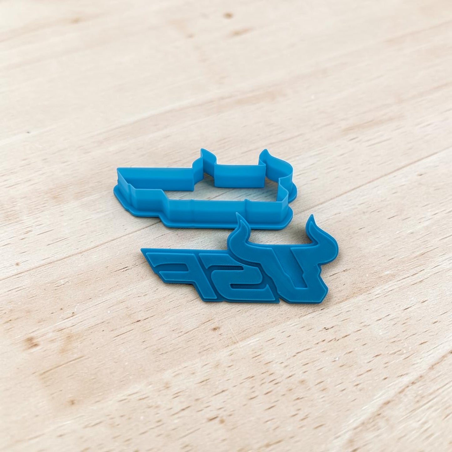 Blue cookie cutters with a logo on a light wooden surface