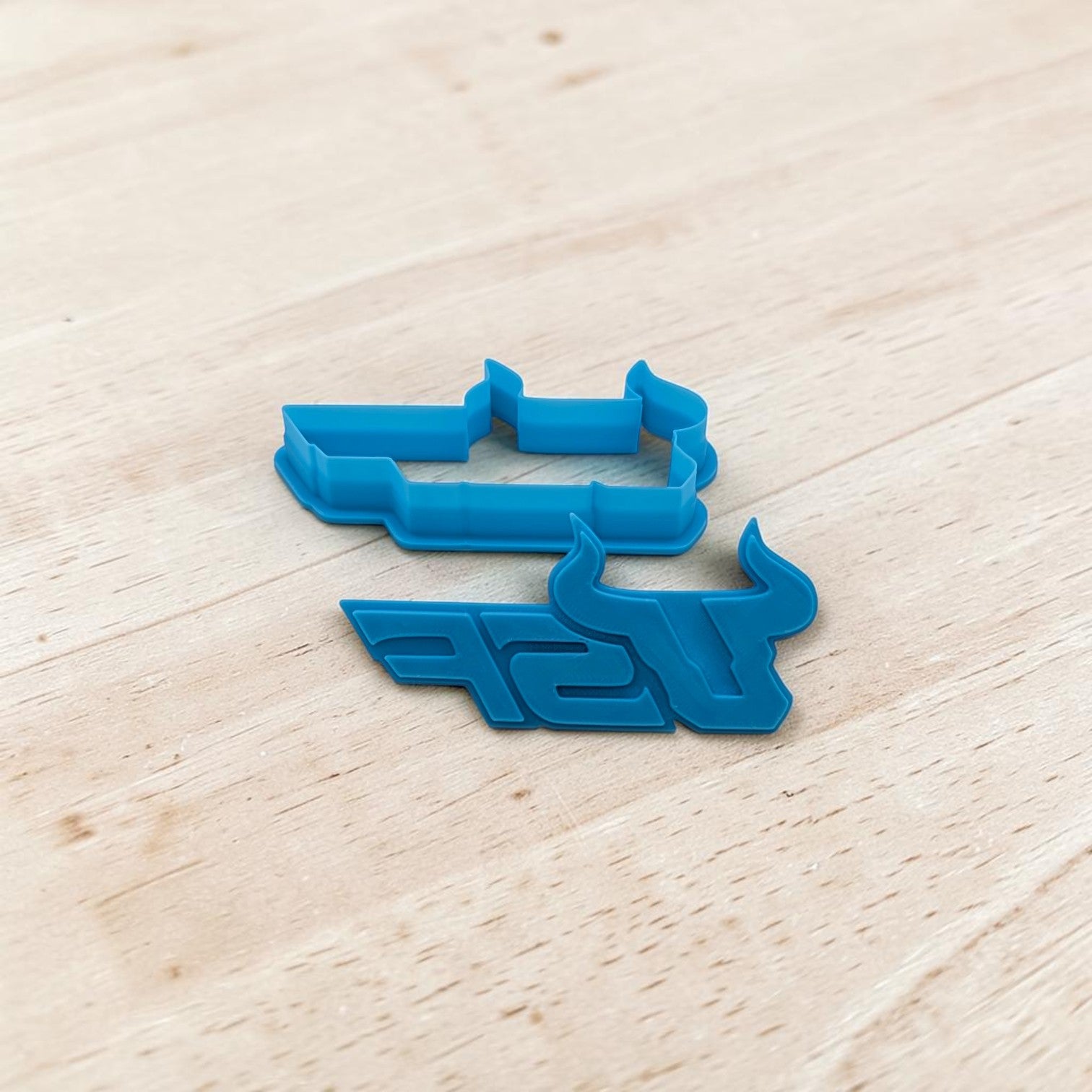 Blue cookie cutters with a logo on a light wooden surface