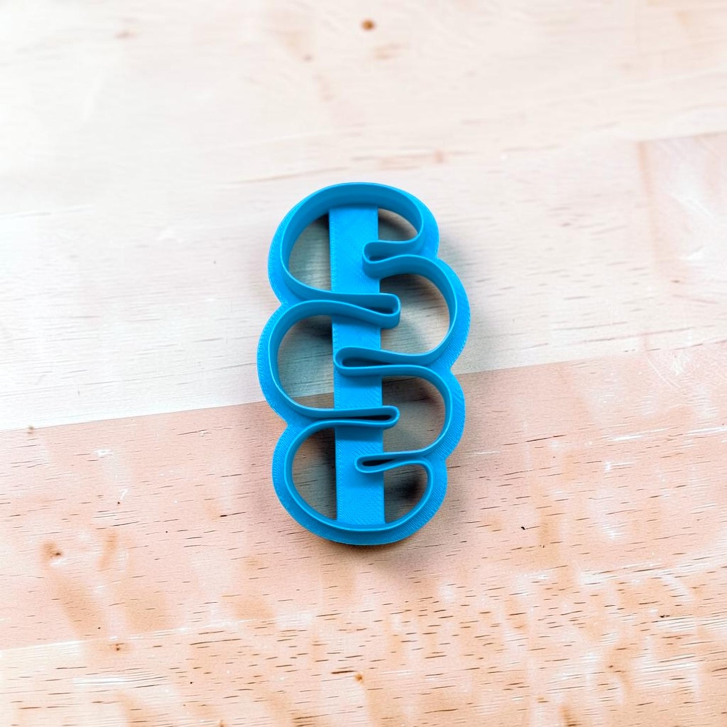Blue cookie cutter with a unique design on a wooden surface