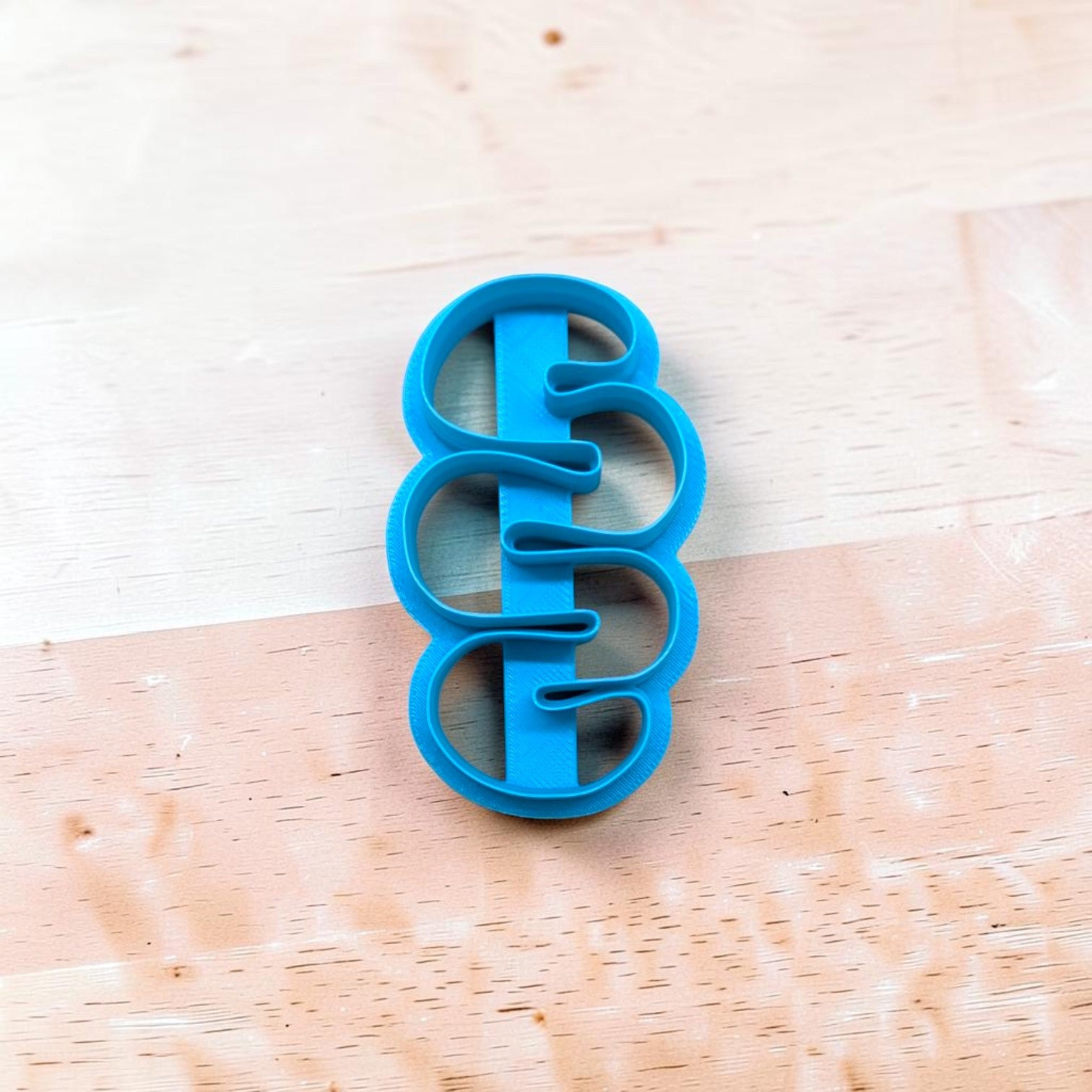 Blue cookie cutter with a unique design on a wooden surface