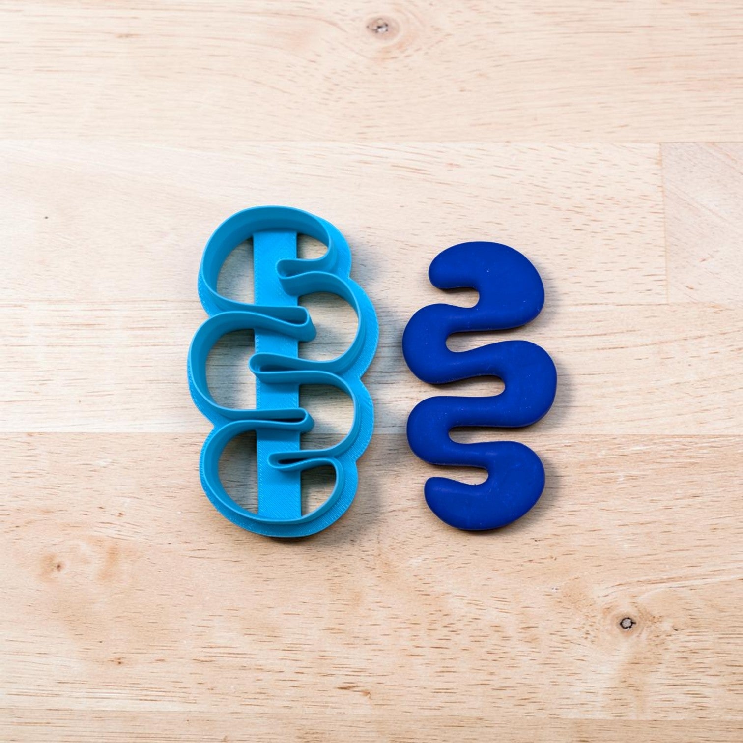 Blue cookie cutter shaped like a DNA double helix on a wooden surface