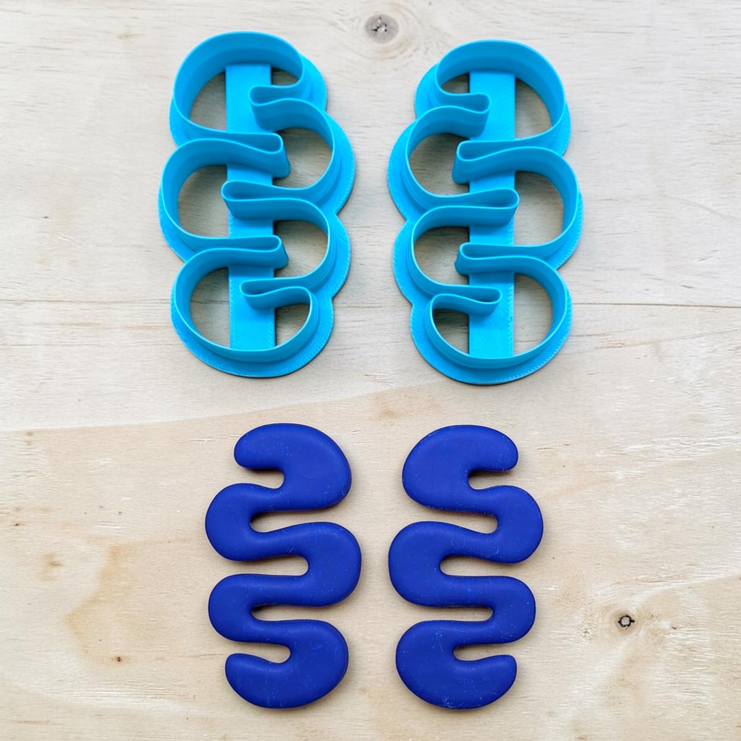Blue cookie cutters shaped like a wavy line on a wooden surface