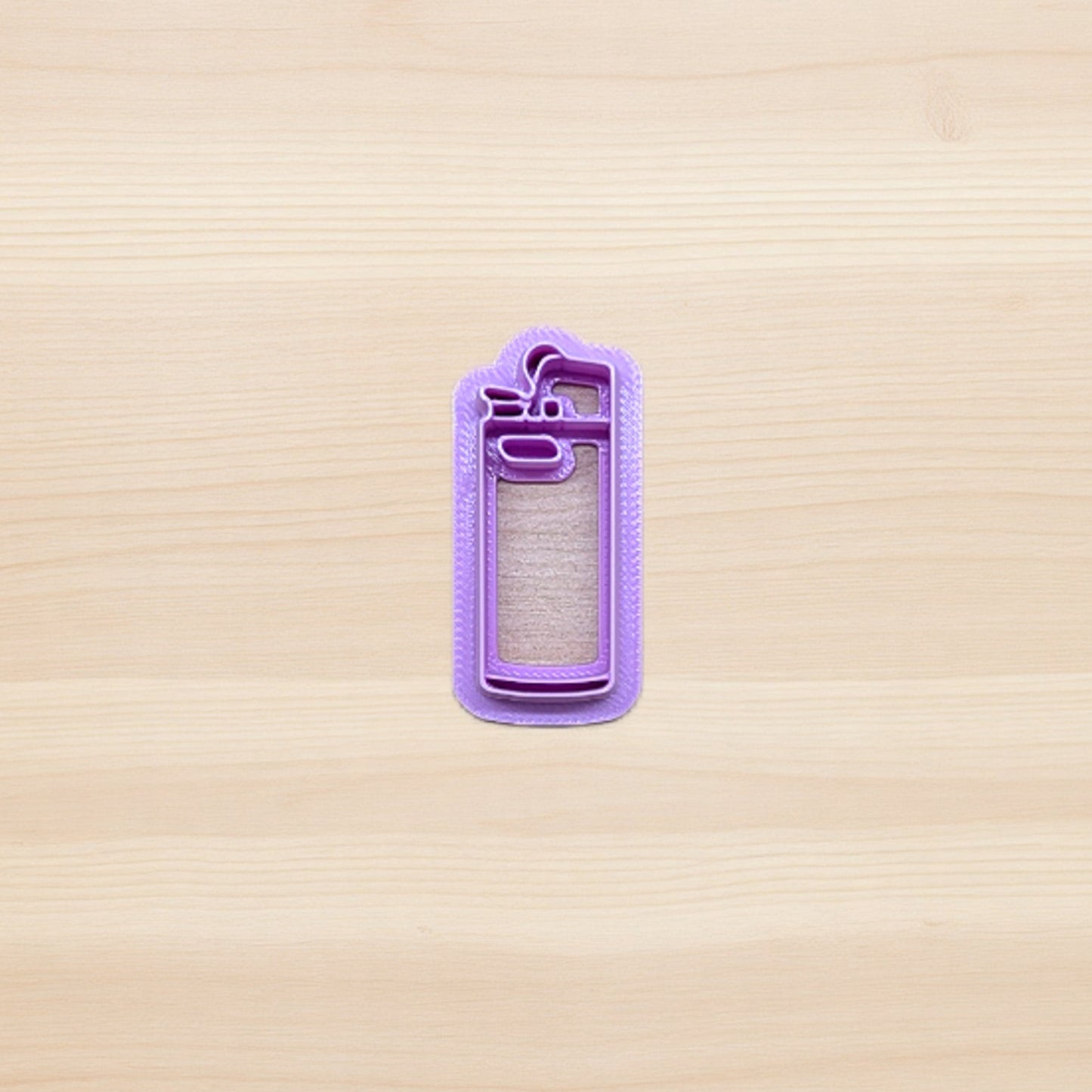 purple plastic cigarette lighter shape cookie and polymer clay cutter on wooden surface