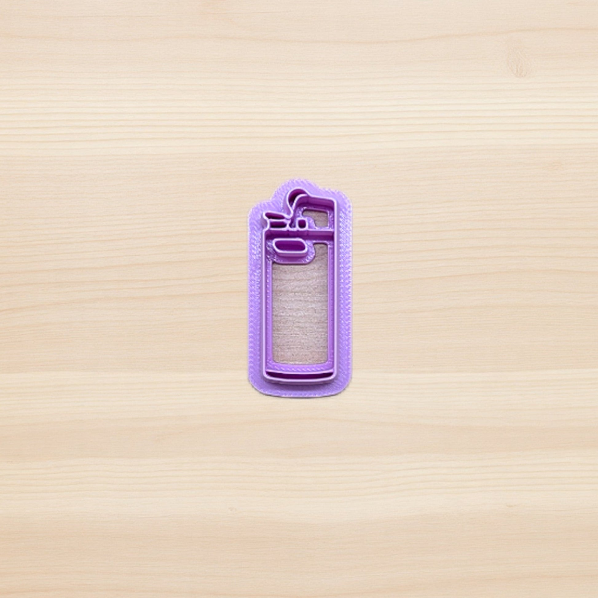 purple plastic cigarette lighter shape cookie and polymer clay cutter on wooden surface