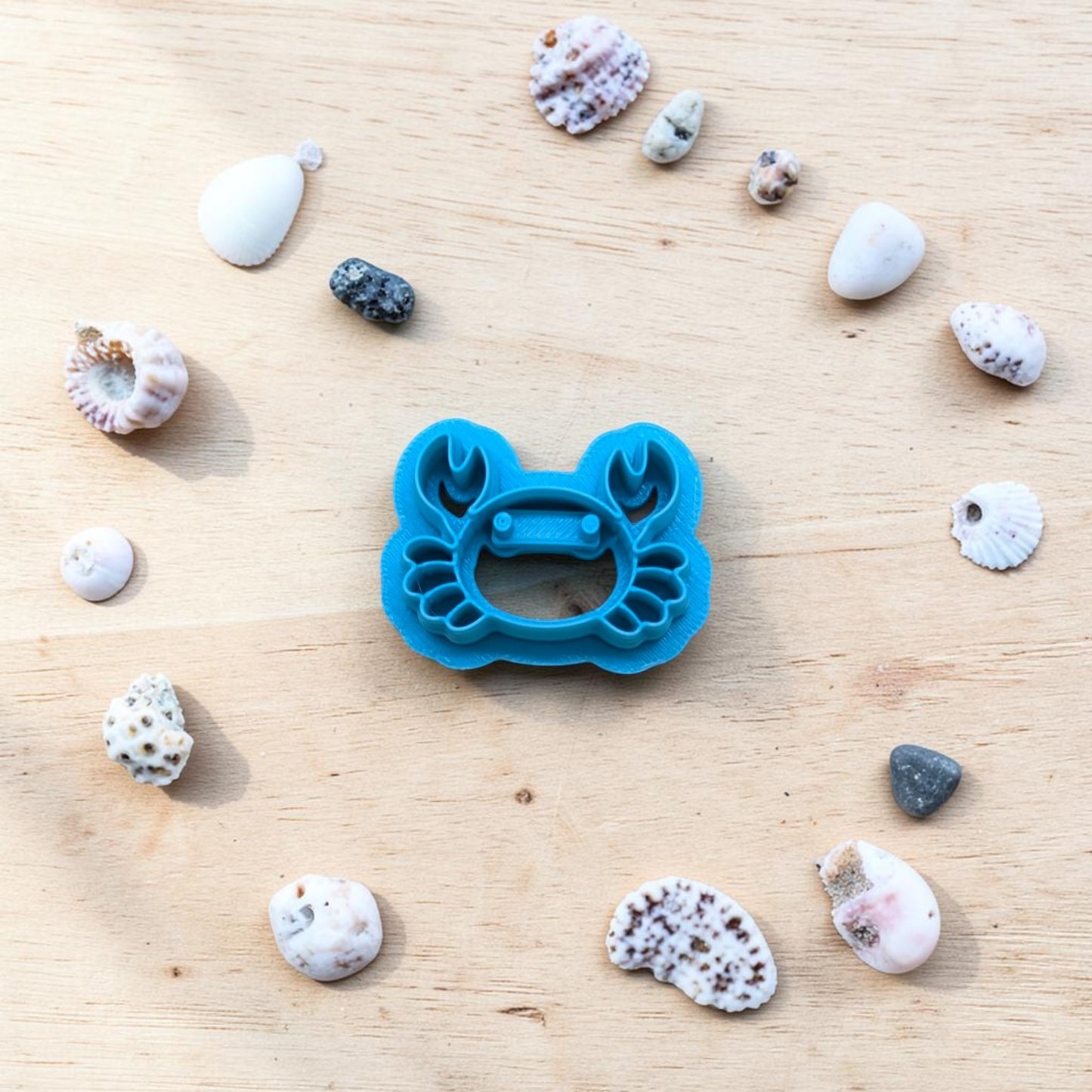 plastic crab-shaped cookie cutter on light color wood surface