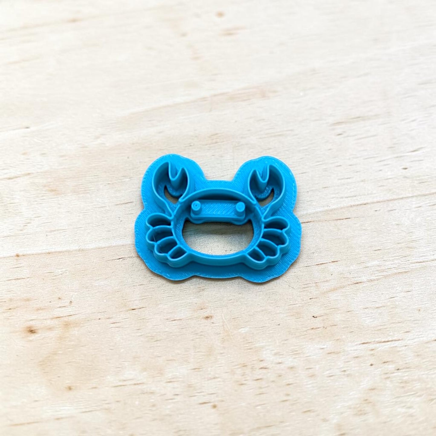 Blue crab-shaped cookie cutter on a light wooden surface