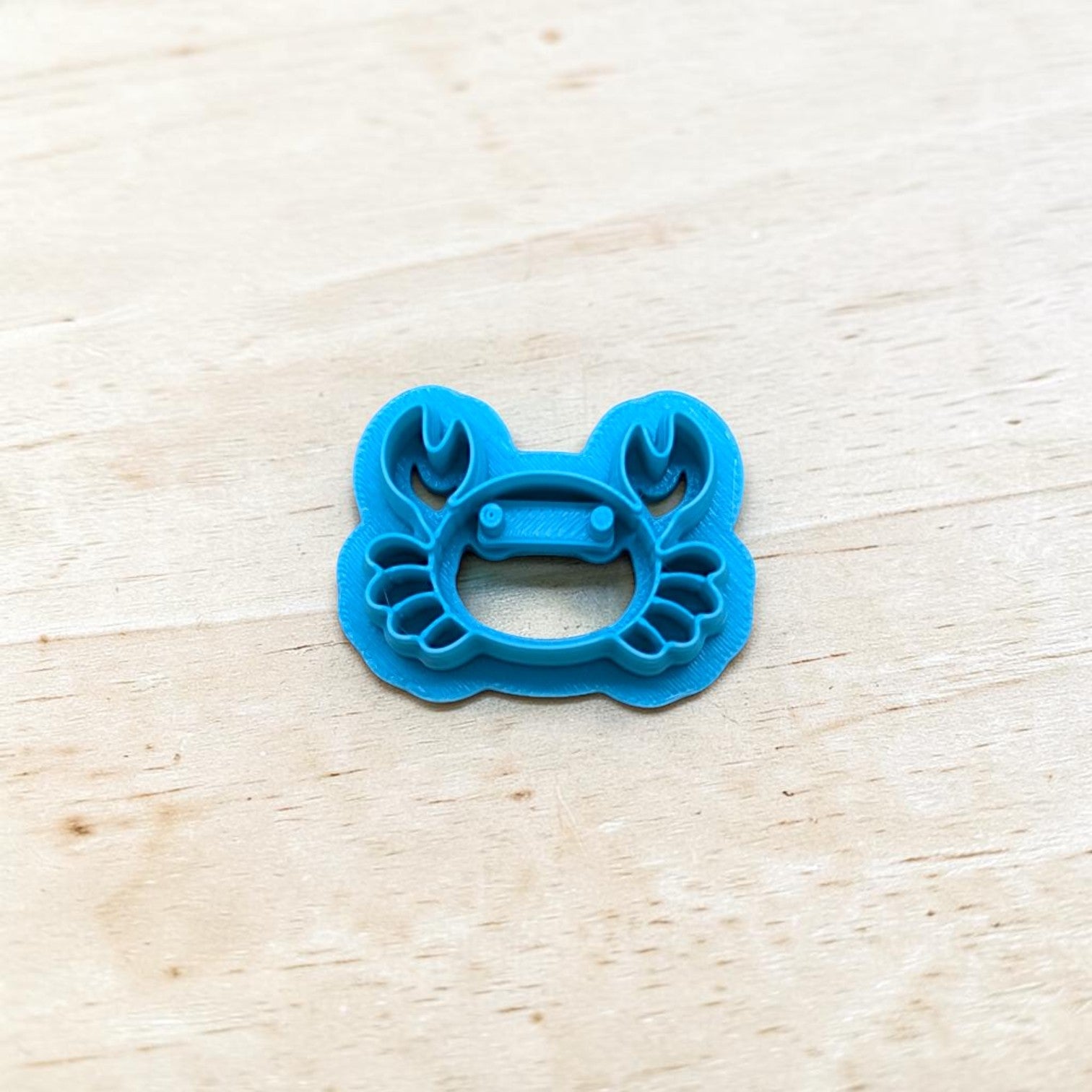 Blue crab-shaped cookie cutter on a light wooden surface