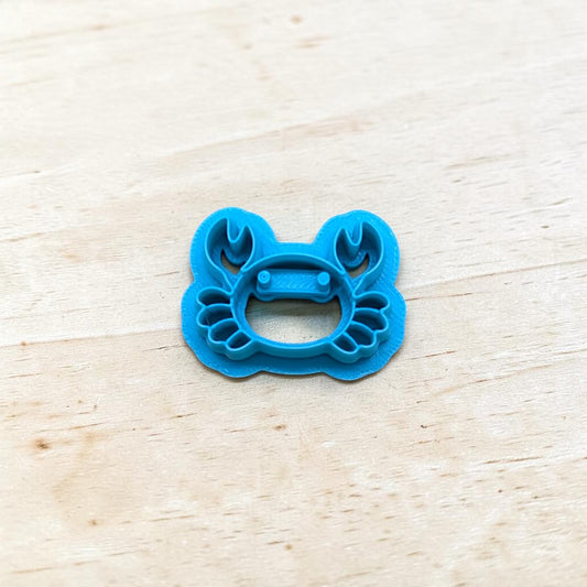 Blue crab-shaped cookie cutter on a light wooden surface